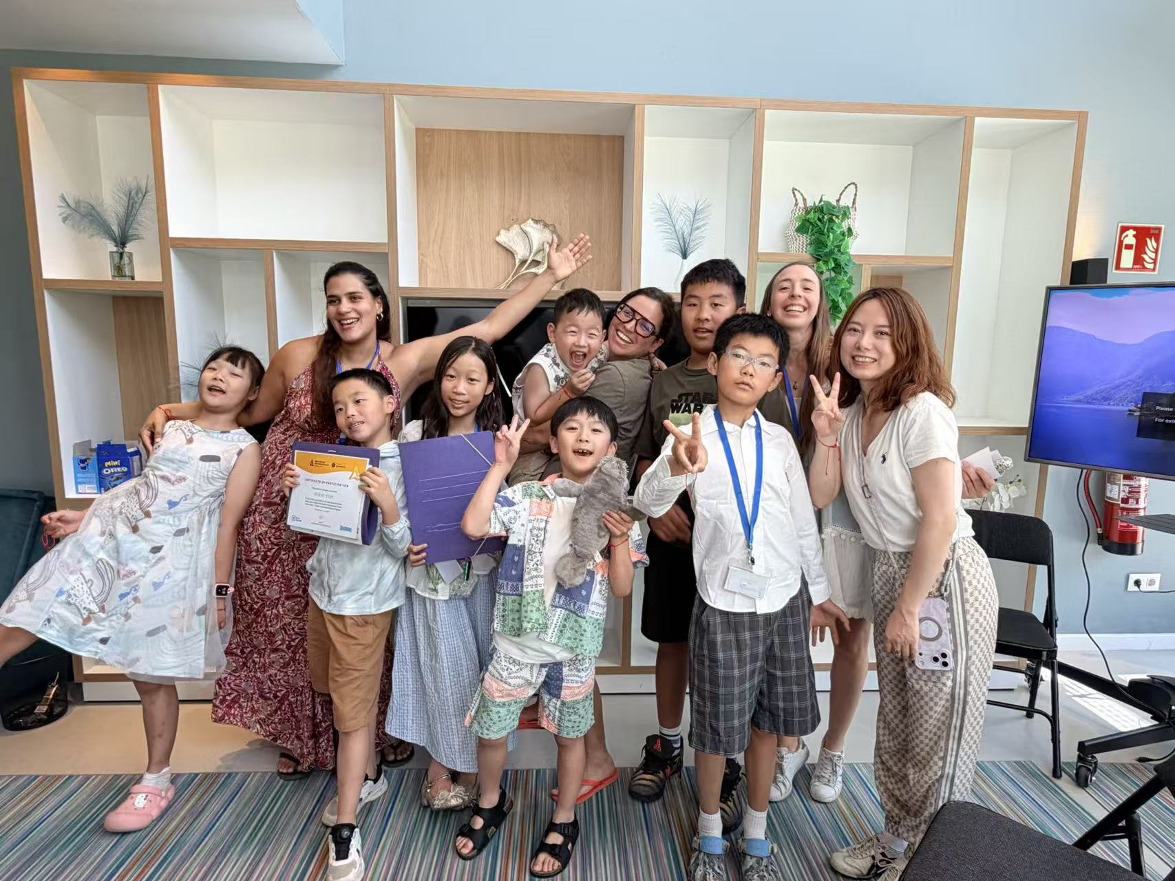 Children and adults celebrating together, one holding a certificate of participation