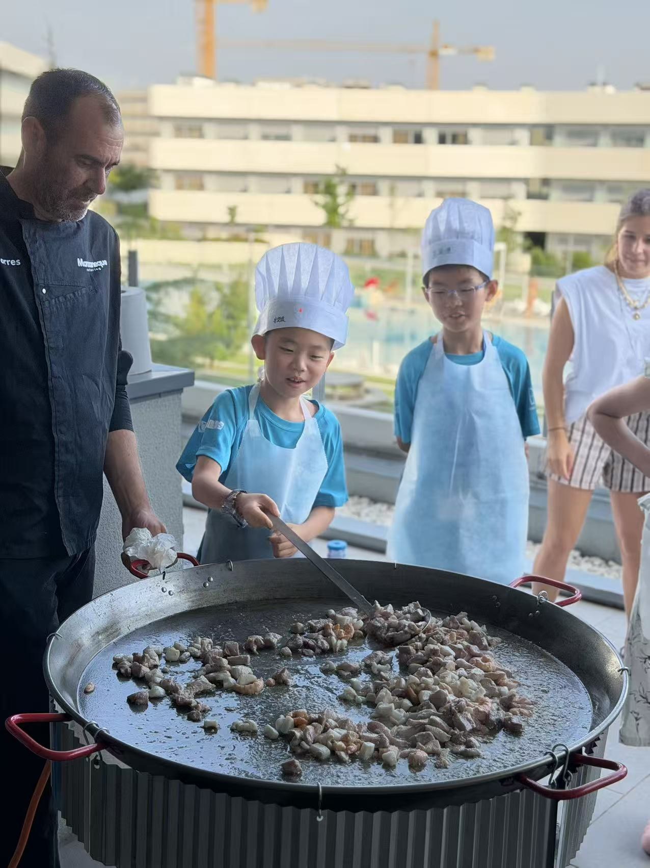 Children preparing paella together with the chef